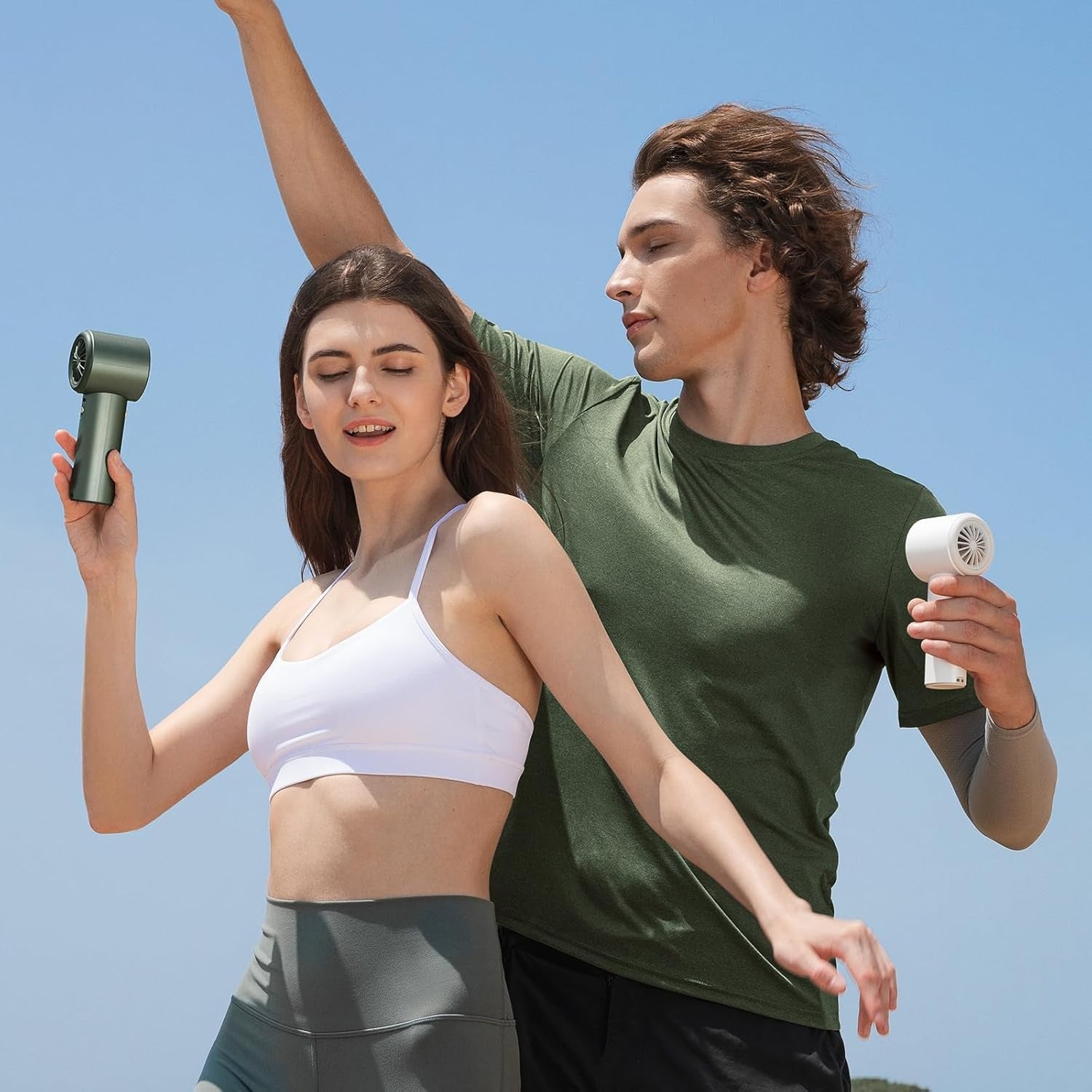 Portable mini handheld fan in green and white used by active young adults outdoors