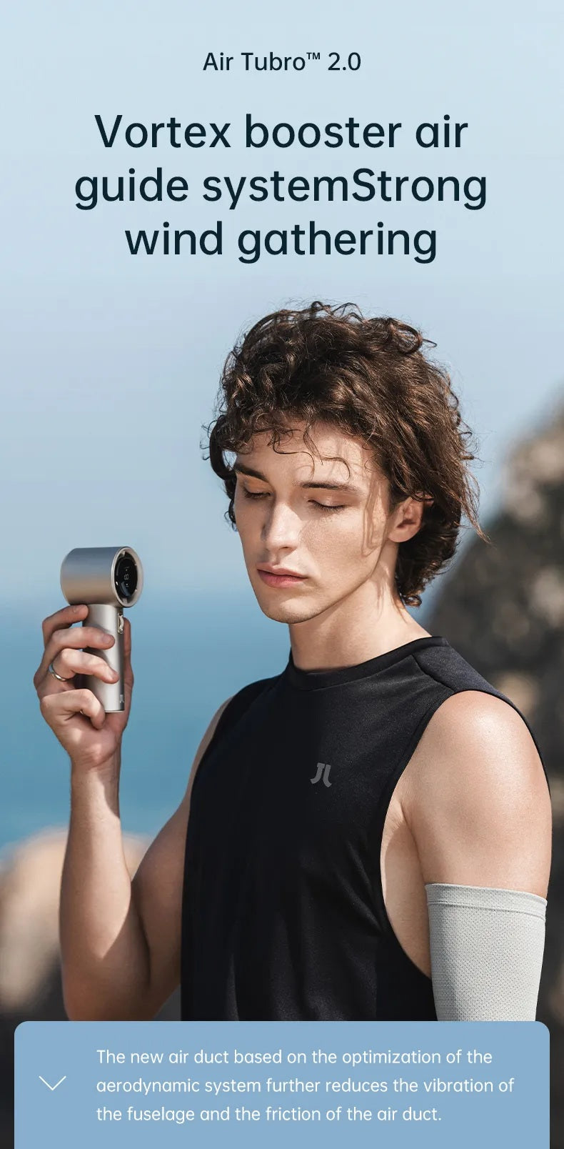 Portable mini handheld fan in silver held by a woman wearing a black sleeveless top outdoors