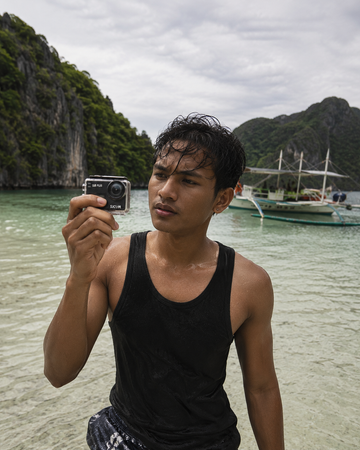 SJCAM SJ8 Plus action camera in waterproof housing being checked on a Philippine sandbar