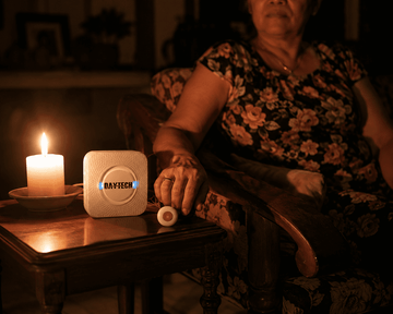 Daytech caregiver pager receiver glowing during a brownout, lit by candlelight in a Filipino home
