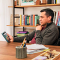 Man using an HD Tablet at a wooden desk surrounded by books and stationery for work or leisure.