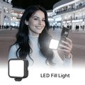 Woman holding C400 Ultra-Bright LED Fill Light while smiling outdoors at night