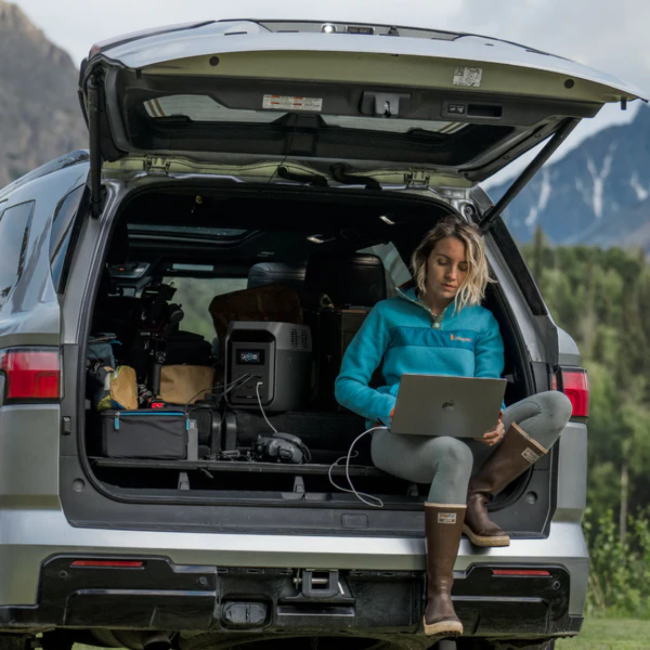 Woman using a laptop in an SUV with a VMIDirect portable power station for outdoor power needs