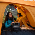 Ecoflow River 3 Max Plus Portable Power Station charging devices inside a camping tent with two people outdoors