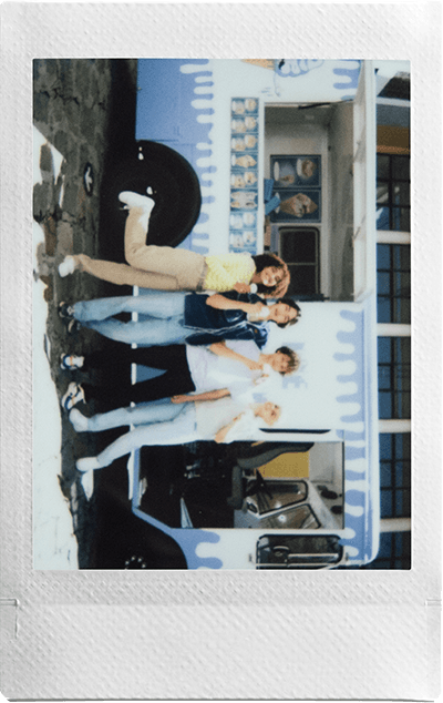 Group of friends posing in front of a colorful food truck with a Fujifilm Instax Mini camera