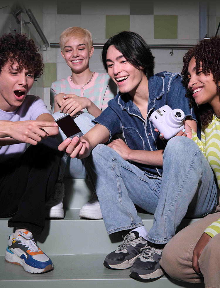 Group of friends enjoying photos taken with the Fujifilm Instax Mini camera in a fun setting