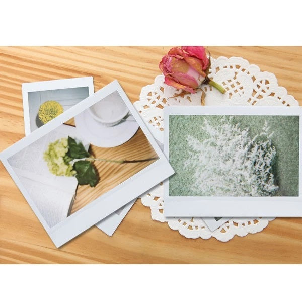 Fujifilm Instax Wide Glossy Film 10 20 Sheets displayed with floral prints on a wooden surface