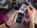 Person holding Mini Evo Hybrid Instant Film Camera with a printed photo in a festive setting