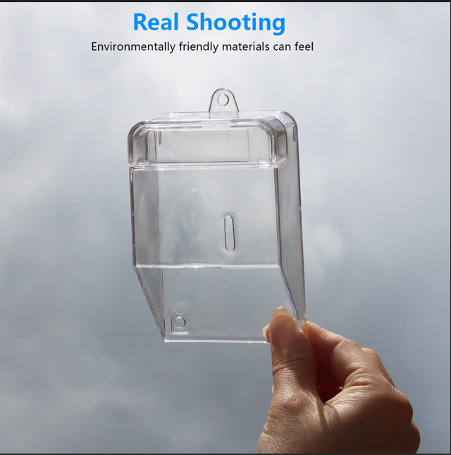 Clear waterproof doorbell cover held in hand with cloudy sky background