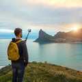 Man using GXCT MT-41 Mini Tripod for sports and action camera against a scenic sunset backdrop