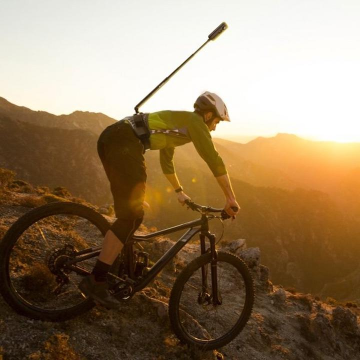VMIDirect Invisible Selfie Stick attached to a cyclist capturing scenic mountain views at sunset