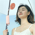 Mini portable fan USB rechargeable attached to umbrella blowing air on woman outdoors