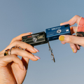 Two Kodak CHARMERA Keychain Digital Cameras in hands, one black and one gold, perfect for capturing memories