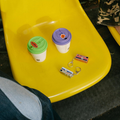 CHARMERA Keychain Digital Camera placed on a yellow chair next to colorful coffee cups