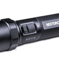 Close-up of a rechargeable tactical flashlight with textured grip and power button