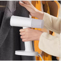 Portable Garment Steamer in use to remove wrinkles from a gray jacket for easy garment care