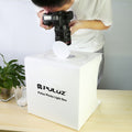 Person using a camera with a LED Photo box for product photography setup on a table.