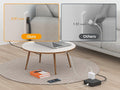 Flat plug power strip extension cord plugged into wall behind couch with laptop and phone charging