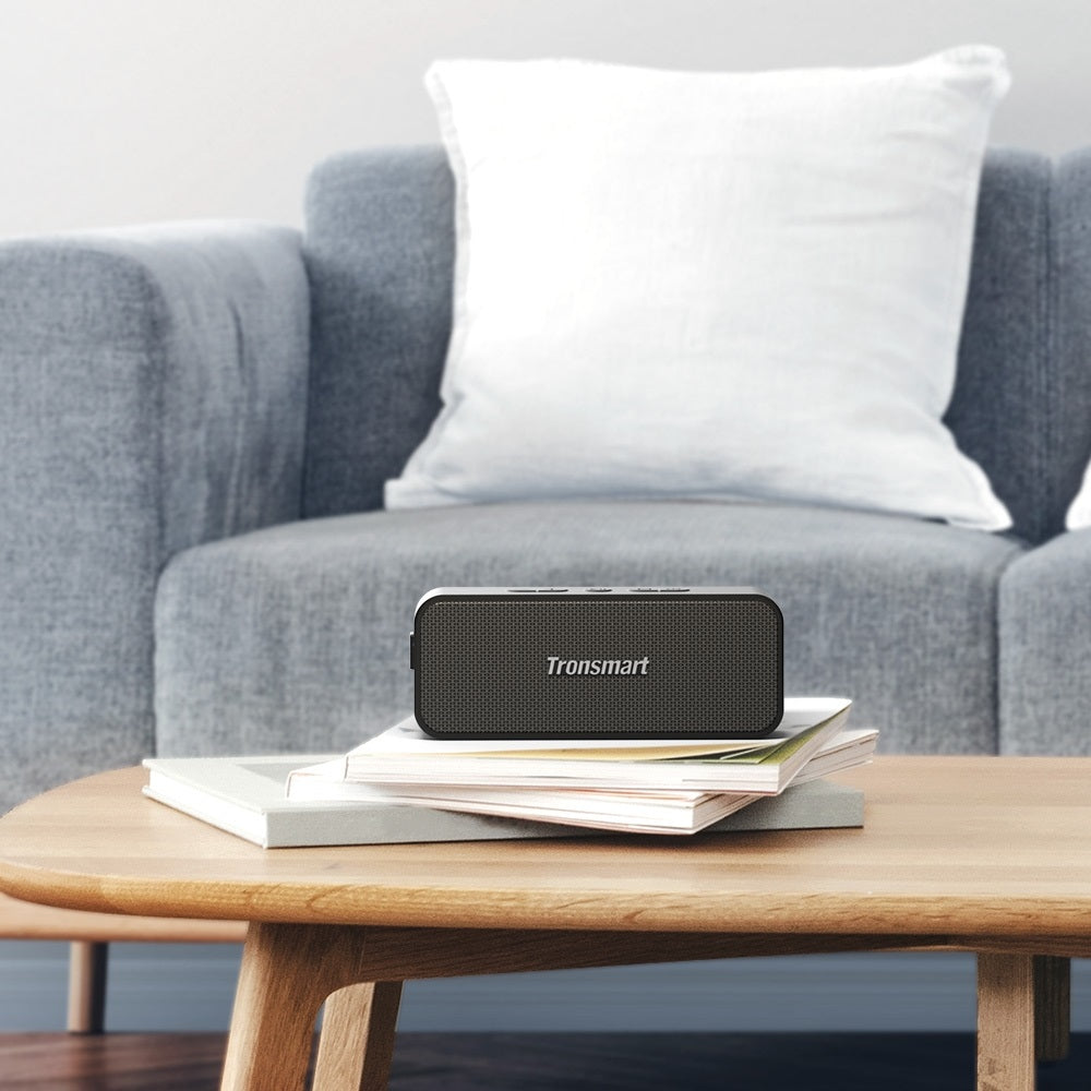 Tronsmart Bluetooth Speaker on a coffee table with books, designed for clear sound and portability