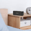 Tronsmart Bluetooth Speaker on a wooden nightstand with modern design for home use