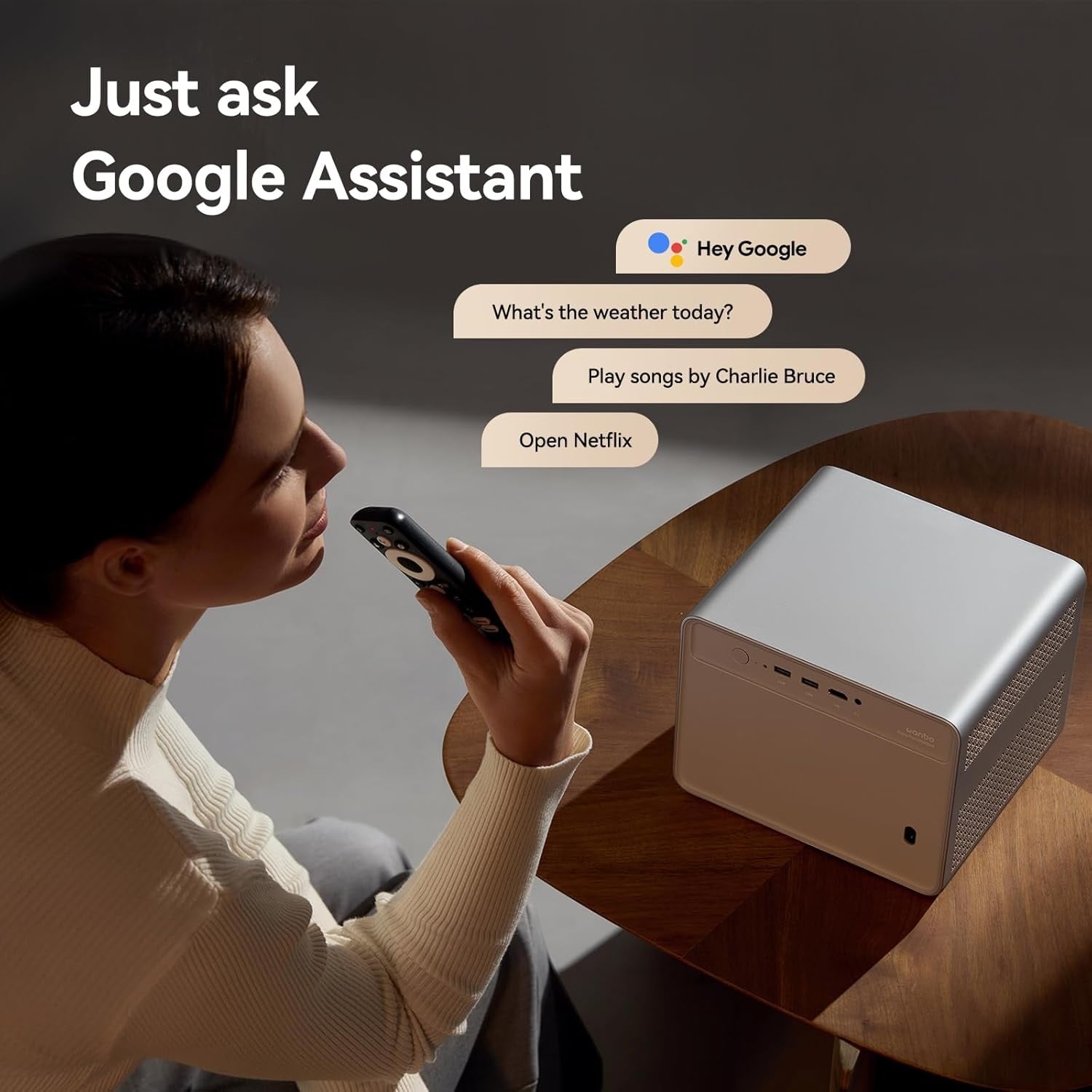 4K smart home projector on wooden table with woman using remote and Google Assistant voice commands