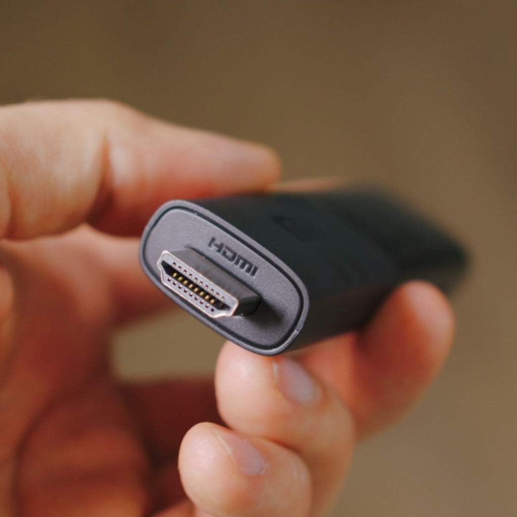 Xiaomi TV Stick shown in hand with HDMI connection for streaming convenience