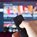 User holding a remote control for a TV connected to a Xiaomi TV Stick streaming content