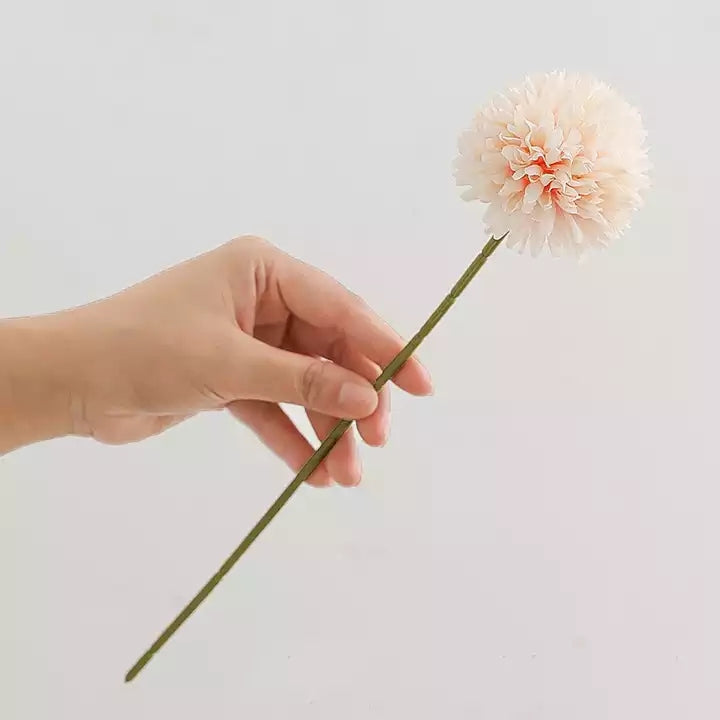 Hand holding an artificial flowers silk dahlia in soft peach color on a green stem