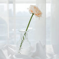 Elegant artificial flowers silk arrangement in a clear glass vase with soft draped fabric
