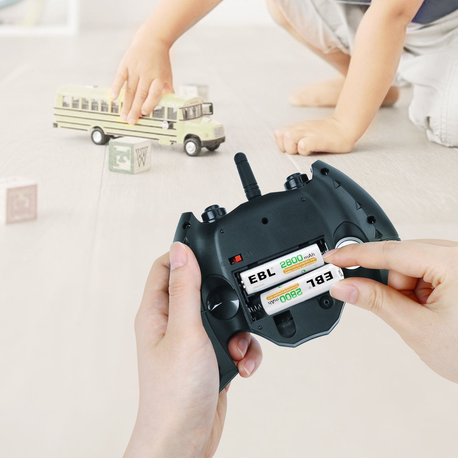 Hands inserting EBL 2800mAh AA rechargeable batteries into a remote control for a toy vehicle