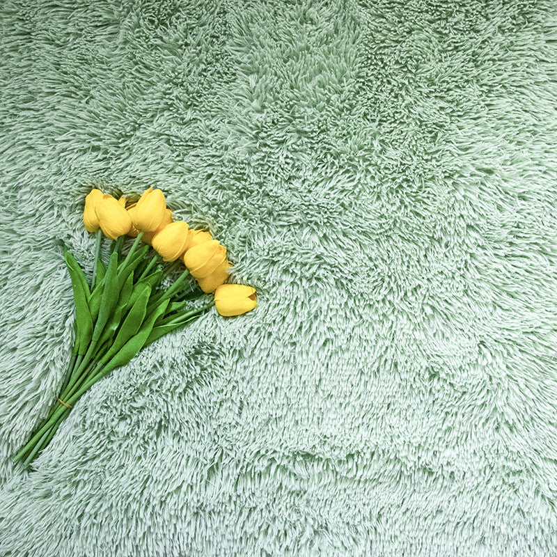 Soft green Faux Fur Makeup Prop Mat with a bouquet of yellow tulips on top