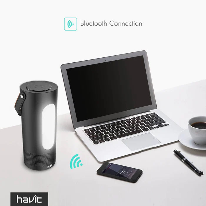Havit Bluetooth Speaker on a desk next to a laptop and phone, showing Bluetooth connection feature