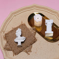 Linen Mat Photo Props with Decorative White Busts and a Candle on a Gold Tray