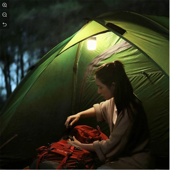 VMIDirect Portable Tourist Lamp illuminating a tent while a person organizes camping gear