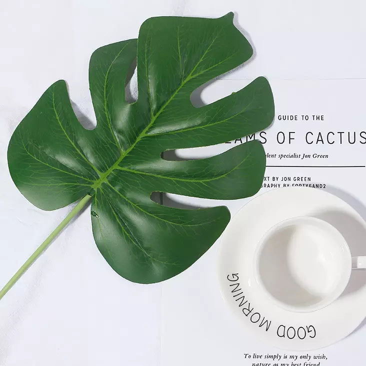 Simulation Artificial Green Plant Leaf on a Table with a Coffee Cup and Book