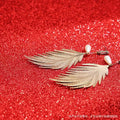 VMIDirect Sparkling Sky Background featuring gold leaf earrings with pearl accents and a glittery red backdrop