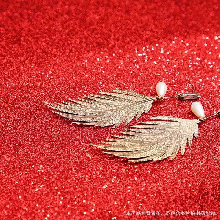 VMIDirect Sparkling Sky Background featuring gold leaf earrings with pearl accents and a glittery red backdrop