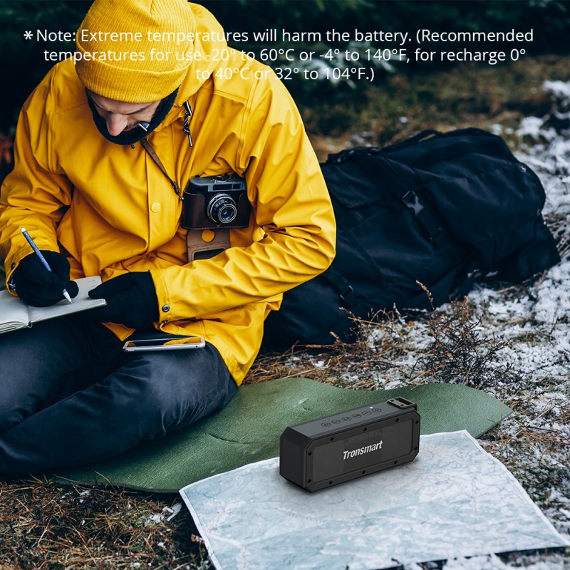 Portable Transmart Bluetooth Speaker on a grass mat with a person writing in a notebook outdoors