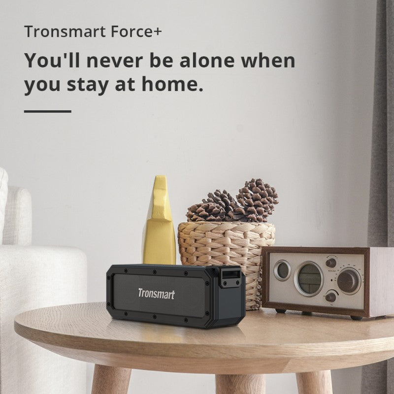 Tronsmart Force+ Bluetooth Speaker on a table next to a vintage radio and decor items