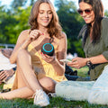 Two friends enjoying music outdoors with a VMIDirect portable speaker in a park