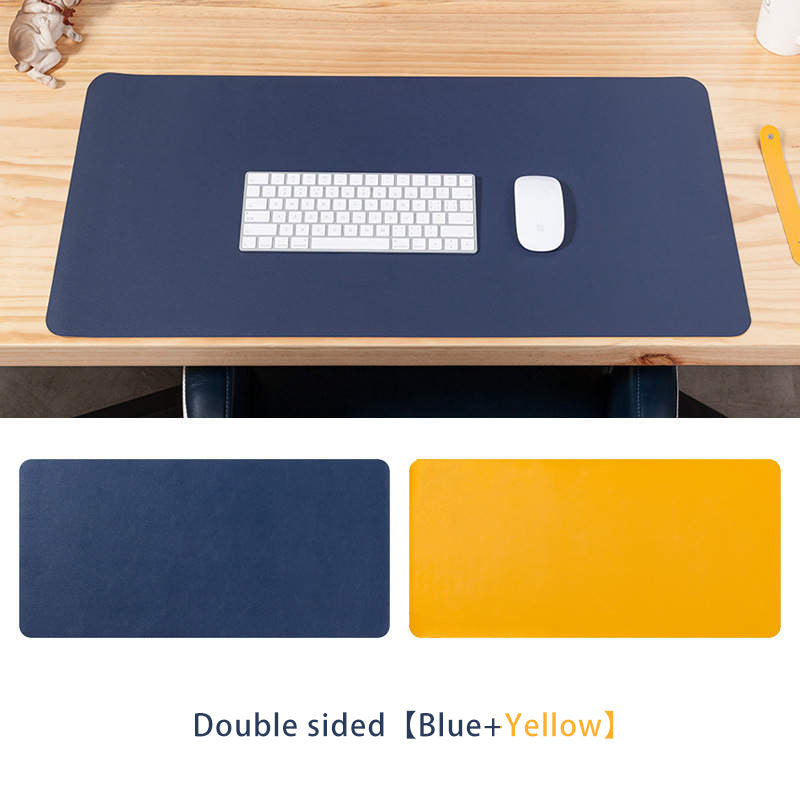 Double sided leather desk pad in blue and yellow with a keyboard and mouse on a wooden desk