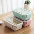 Three 850ml Wheat Straw Rectangular Bento Lunch Boxes in pink, green, and beige on a wooden table